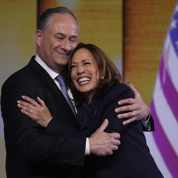 23.08.2024, USA, Chicago: Die demokratische Präsidentschaftskandidatin Kamala Harris umarmt den Second Gentleman Douglas Emhoff nach der Nominierung während der Democratic National Convention. Foto: B ...