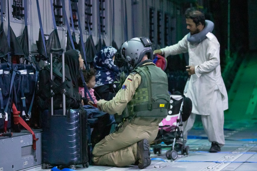 Ein Ladungsmeister der Bundeswehr hilft Afghanen vor dem Abflug aus Kabul beim Anschnallen im Transportflugzeug. 