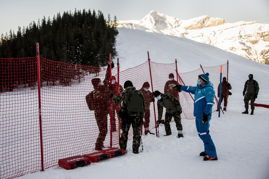 11.01.2021, Schweiz, Wengen: Ski alpin: Vor dem Weltcup, Abfahrt, Herren: Schweizer Soldaten sperren den Zuschauerbereich vor der Skipiste mit einem Zaun ab. Die diesj