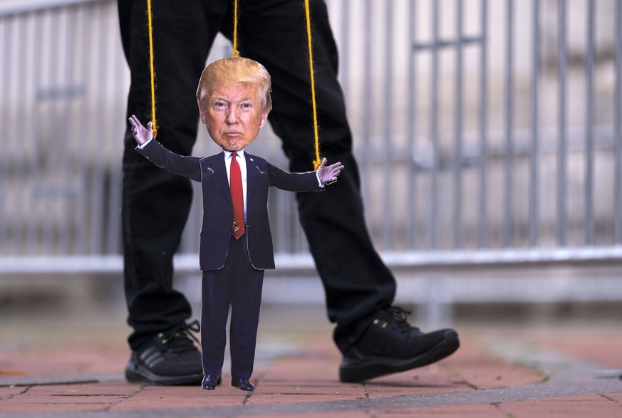A protester holds a marionette puppet of President Donald Trump as they participate in a demonstration sponsored by various humans rights groups protesting what they say is Trump s inappropriate relat ...