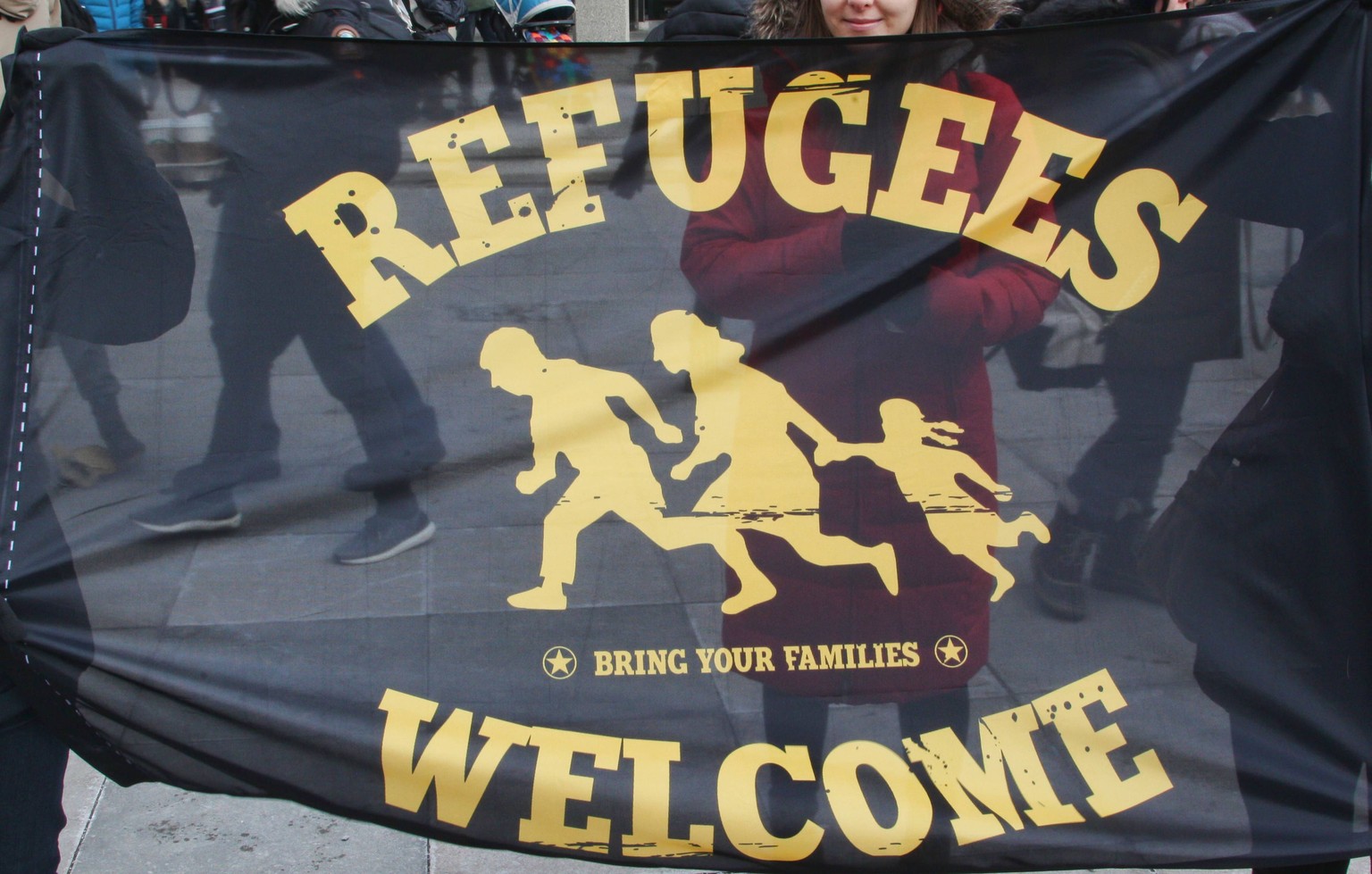 February 4, 2017 - Toronto, Ontario, Canada - Women hold a flag saying Refugees Welcome as thousands of Canadians take part in a massive protest against President Trump s travel ban on Muslims during  ...