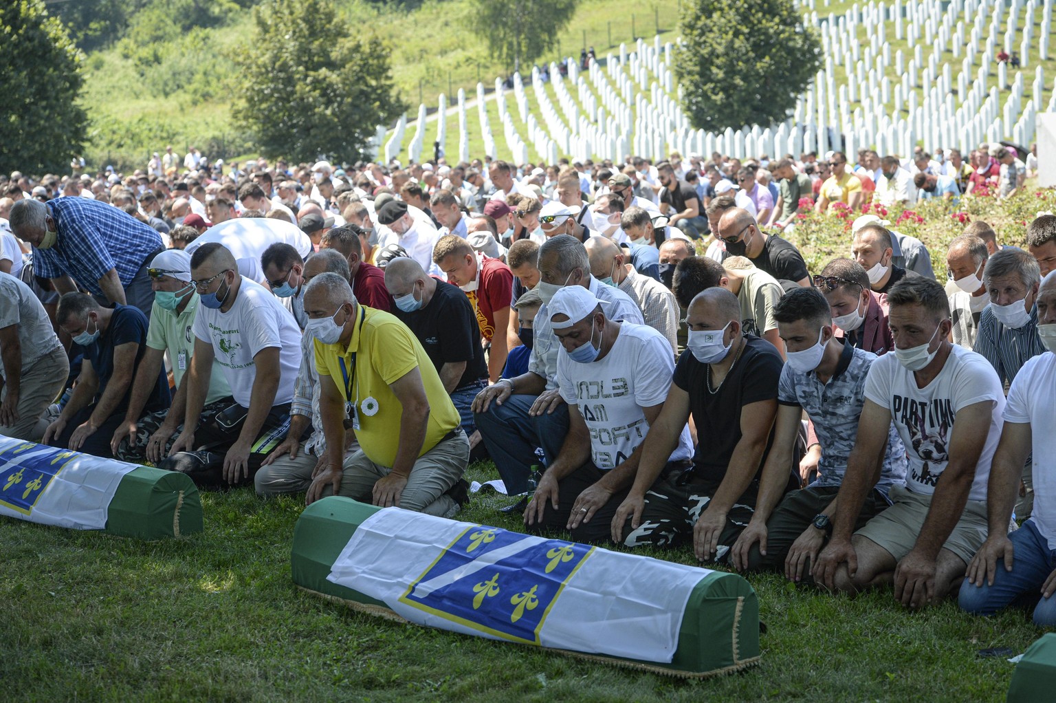 Bosnians pray by the coffins of nine massacre victims in Potocari, near Srebrenica, Bosnia, Saturday, July 11, 2020. Mourners converged on the eastern Bosnian town of Srebrenica for the 25th anniversa ...