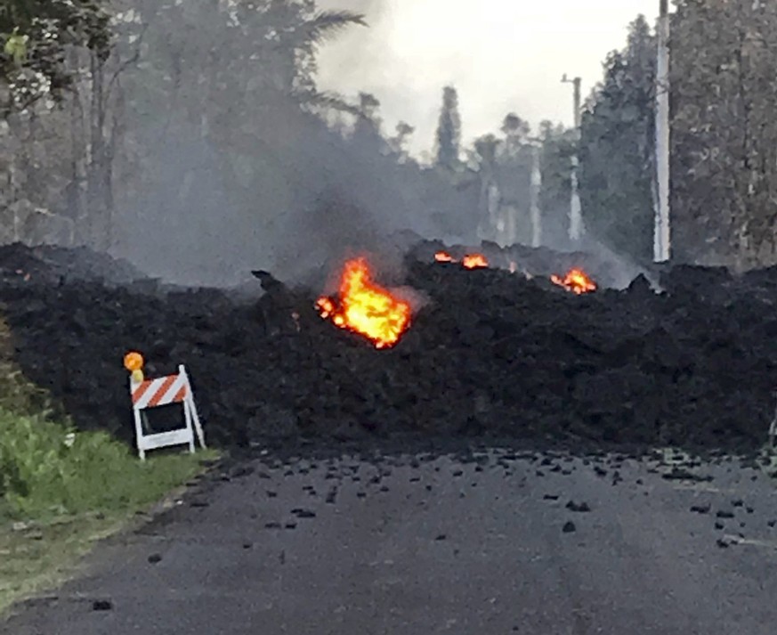 This photo provided by Hawaii Electric Light shows lava flowing over Mohala Street in the Leilani Estates area near Pahoa on the Big Island of Hawaii Friday, May 4, 2018. Nearly 1,500 people have fled ...