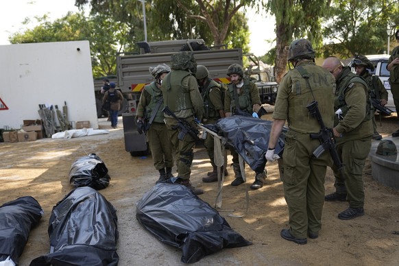 Israeli soldiers carry the body of a person killed by Hamas militants in Kibbutz Kfar Azza on Tuesday, Oct. 10, 2023. Hamas militants overran Kfar Azza on Saturday, where many Israelis were killed and ...