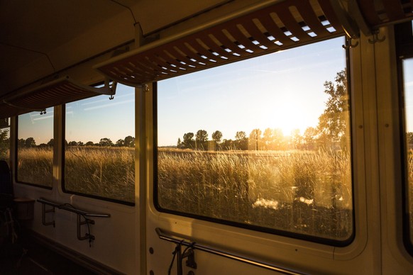 Ausblick aus einem Zug-Waggon auf die Felder bei Sonnenuntergang in Norddeutschland.