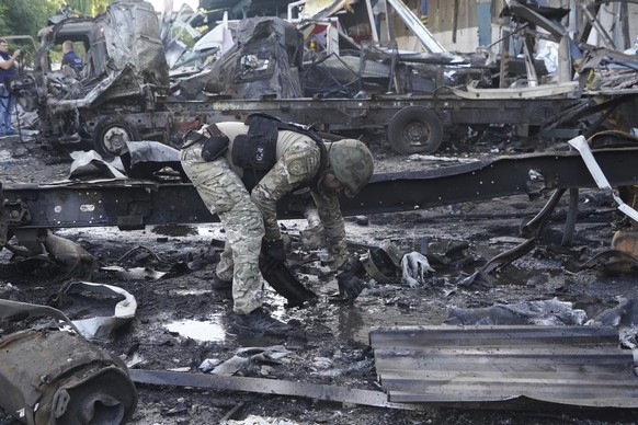 30.06.2024, Ukraine, Charkiw: Ein Polizeibeamter sammelt Beweise nach einem russischen Angriff. Foto: Andrii Marienko/AP/dpa +++ dpa-Bildfunk +++