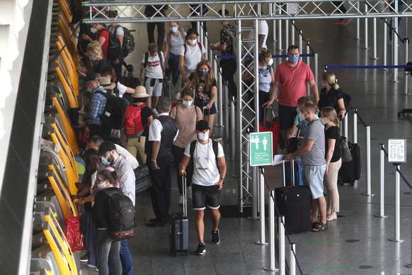 Nach dem Wegfall der meisten Reisewarnungen während der Coronakrise nimmt der Flugverkehr langsam wieder Fahrt auf. Wartende Fluggäste stehen mit Mund-Nase-Abdeckung an den Check-in Automaten der Luft ...