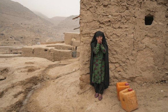 FILE - An Afghan girl warms up her hands as she is resting from carrying the water in Balucha, Afghanistan, Monday, Dec. 14, 2021. The Middle East is one of the most vulnerable regions in the world to ...