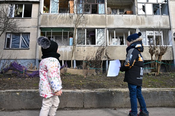 LVIV, UKRAINE – 15. FEBRUAR 2024 – Ein Junge und ein Mädchen stehen vor einem Wohnblock, in dem während des russischen Raketenangriffs durch die Druckwelle die Fenster herausgeschlagen wurden, Lviv, Westukraine. Im E...