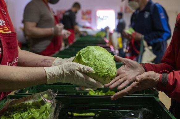 In der Laib und Seele- Ausgabestelle in Berlin verteilt eine ehrenamtliche Mitarbeiterin einen Eisberg Salat. Angesichts steigender Lebensmittelpreise, höherer Energiekosten und des Ukraine-Kriegs ste ...