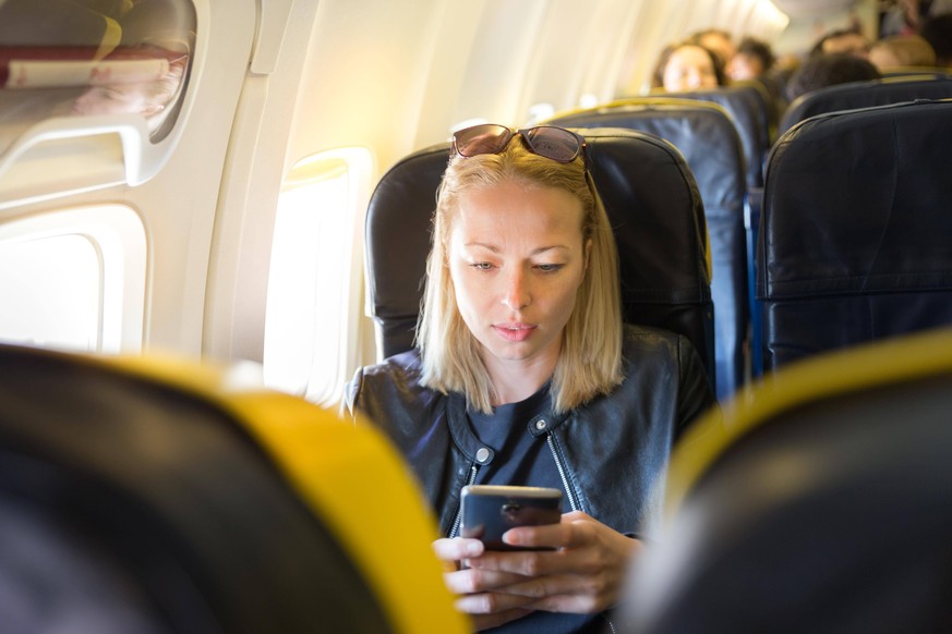 Woman using mobile phone as entertainment on airplane during commercial flight. ,model released, Symbolfoto PUBLICATIONxINxGERxSUIxAUTxONLY Copyright: xkastox Panthermedia25798726