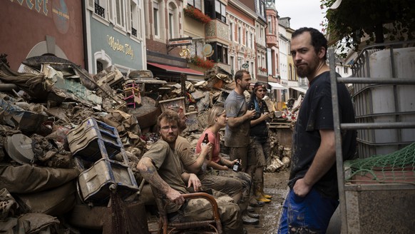 People take a break from cleaning the debris from the flood disaster in Bad Neuenahr-Ahrweiler, Germany, Monday July 19, 2021. More than 180 people died when heavy rainfall turned tiny streams into ra ...