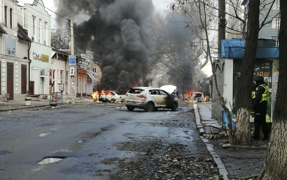 24.12.2022, Ukraine, Cherson: Autos brennen und Rauch steigt auf, nachdem ein russischer Raketenangriff das Stadtzentrum getroffen hat. Bei einem russischem Beschuss des Zentrums der südukrainischen S ...
