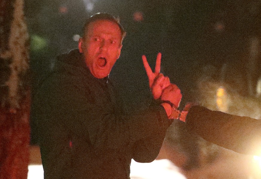 Alexej Nawalny, Oppositionspolitiker und Kremlkritiker, macht ein V-Zeichen, während er in Handschellen von einem Polizeibeamten vor der 2. Abteilung der Direktion des russischen Innenministeriums von Chimki eskortiert wird. Am Sasmtag kam es zu heftigen Protesten im Land.