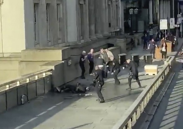 In this grab taken from video made available by @HLOBlog, a man is surrounded by police after an incident on London Bridge, in London, Friday, Nov. 29, 2019. A man wearing a fake explosive vest stabbe ...