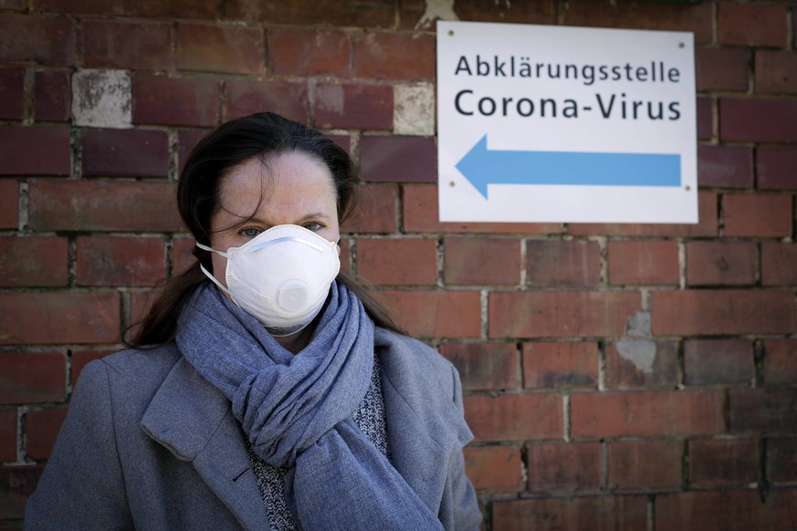 14.03.2020, Berlin, Deutschland - Symbolfoto zur Corona-Krise. Foto: Eine junge Frau mit Mundschutz vor einem Schild mit der Aufschrift Abklaerungsstelle Corona-Virus. *** 14 03 2020, Berlin, Germany  ...