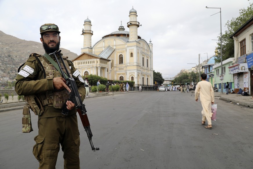 A Taliban fighter stands guard as Afghan people attend Eid al-Adha prayers, in Kabul, Afghanistan, Wednesday, June 28, 2023. Muslims celebrate the holiday to mark the willingness of the Prophet Ibrahi ...