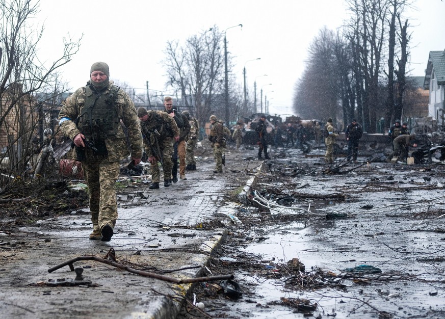 April 3, 2022, Kyiv, Ukraine: Ukrainian soldiers inspect the wreckage of a destroyed Russian armored column on a road in Bucha, a suburb just north of the Capital, Kyiv. As Russian troops withdraw fro ...