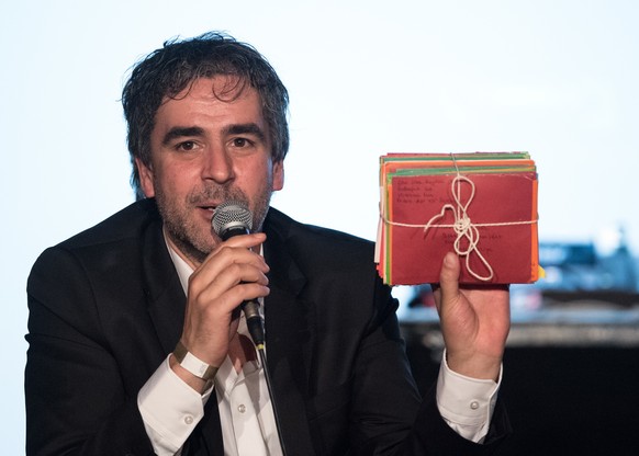 Deniz Yücel zeigt während der Veranstaltung "Auf die Freiheit" im Festsaal Kreuzberg ein Bündel Briefe, die ihm seine Ehefrau mit ins Gefängnis gebracht hat.