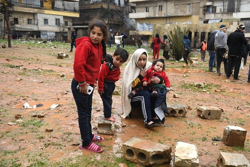 Syria Earthquake 8366431 07.02.2023 A woman with children is seen outside a residential building destroyed by an earthquake, in Aleppo, Syria. A massive 7.8-magnitude earthquake with several powerful  ...