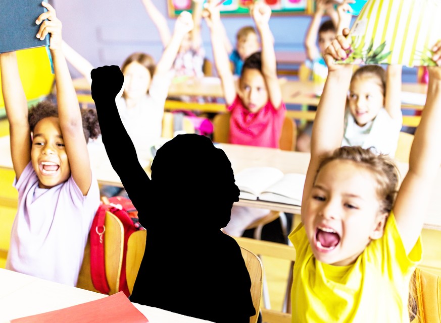 Large group of cheerful students screaming of joy with raised arms in the classroom. Focus is on boy looking at camera.