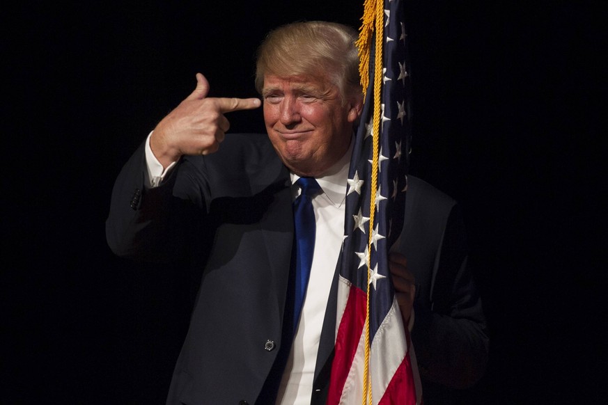 Republican presidential candidate Donald Trump points to an American flag as he walks on stage for a town hall meeting at Pinkerton Academy in Derry, New Hampshire on August 19, 2015. PUBLICATIONxINxG ...