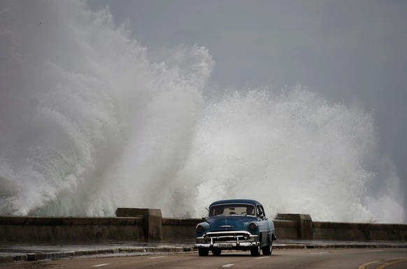 Waves crash against the Malecon, triggered by the outer bands of Hurricane Michael, as man drives past in a classic American car in Havana, Cuba, Tuesday, Oct. 9, 2018. A fast and furious Hurricane Mi ...