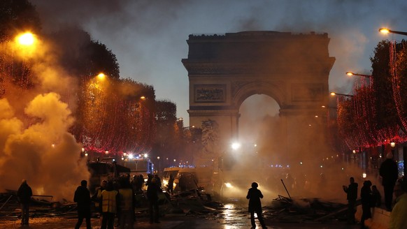 Plumes of smoke are seen near the Arc de Triomphe on the Champs-Elysees avenue decorated with the Christmas lightings during a protest against tax Saturday, Nov. 24, 2018 in Paris. French police fired ...