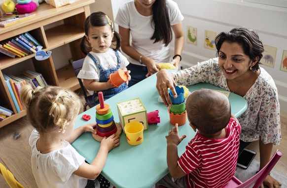 Nursery children playing with teacher in the classroom