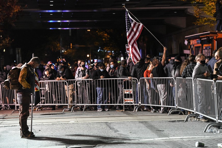 November 5, 2020, Philadelphia, Pennsylvania, USA: A Trump supporter stands alone as protesters supporting Joe Biden gather in fron of the Convention Center in Philadelphia Thursday as the presidency  ...