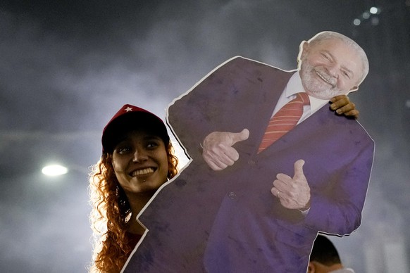 A follower of former Brazilian President Luiz Inacio &quot;Lula&quot; da Silva, who is again running for president, celebrates as she listens to the partial results after general election polls closed ...