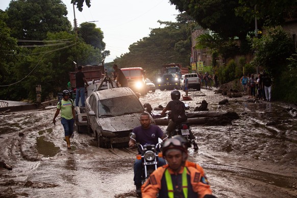 17.10.2022, Venezuela, Maracay: Menschen und Fahrzeuge stecken im Schlamm der durch �berschwemmungen und Erdrutsche auf die Stra�en kam. Heftige Regenf�lle f�hrten zu Hochwasser in der Stadt Maracay i ...