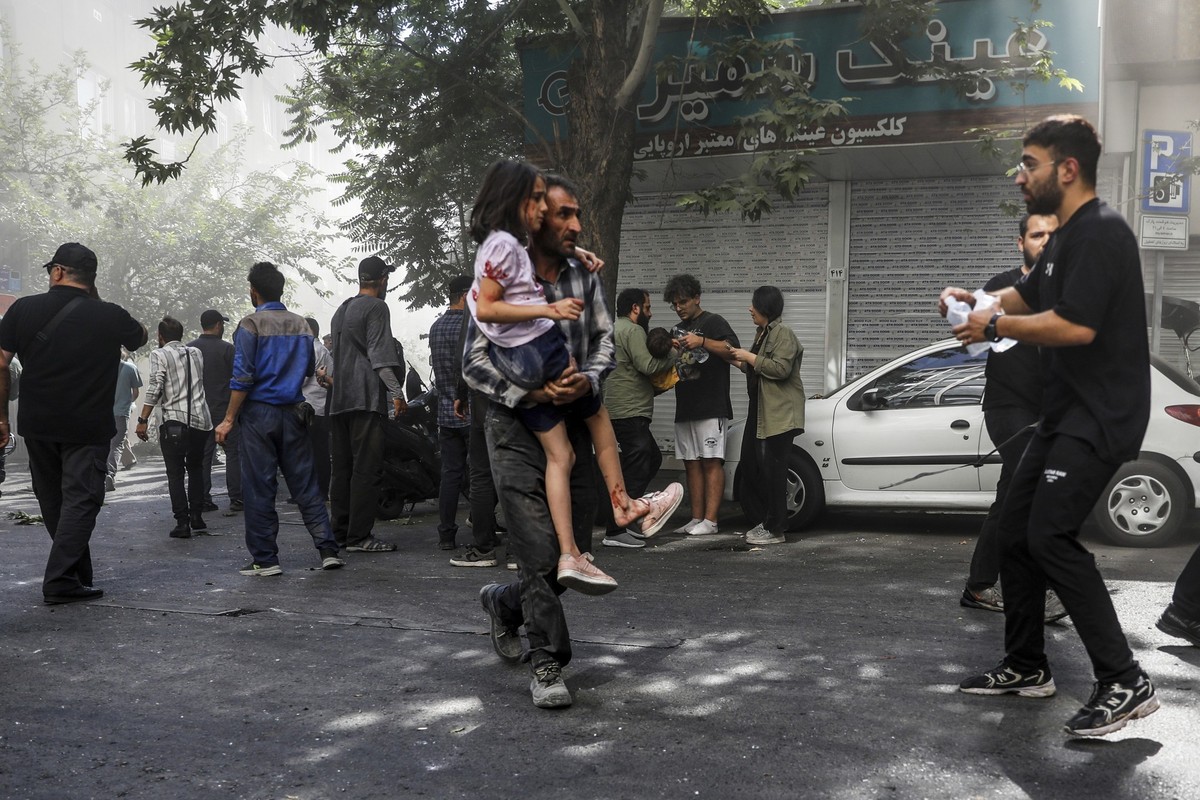 15.06.2025, Iran, Teheran: Ein Mann trägt ein verwundetes Mädchen nach einer Explosion in der Innenstadt von Teheran inmitten der zweitägigen israelischen Luftangriffe auf den Iran. Foto: Morteza Zang ...