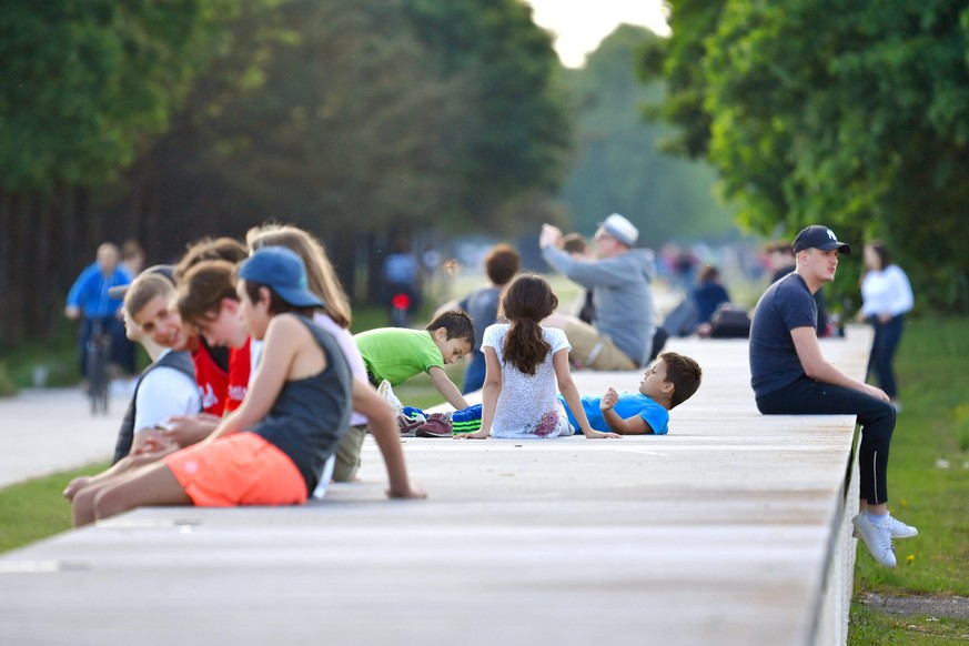 Oeffentliches Leben nach Lockerung der Corona Massnahmen in Bayern / Riemer Park in Muenchen am 10.05.2020. Personen im Freien. Jugendliche,junge Menschen sitzen zusammen auf einer Mauer. Aufenthalt i ...