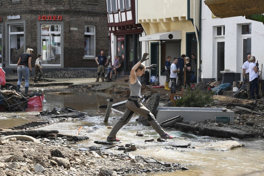 17.07.2021, Nordrhein-Westfalen, Bad Münstereifel: Eine Helferin springt über das Wasser. In der Nacht zum 15.07.2021 verwüstete das Hochwasser der Erft den historischen Kern der Stadt total. Straßen, ...