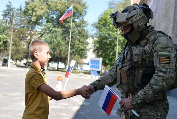 Ukraine Russia National Flag Day 8257831 22.08.2022 A boy shake hands with Russian serviceman at Russian National Flag Day, as Russia s military operation in Ukraine continues, in the town of Volchans ...