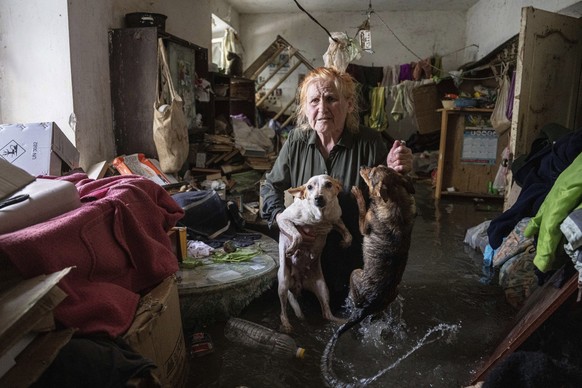 Local resident Tetiana holds her pets, Tsatsa and Chunya, as she stands inside her house that was flooded after the Kakhovka dam blew up overnight, in Kherson, Ukraine, Tuesday, Jun 6, 2023. Ukraine o ...