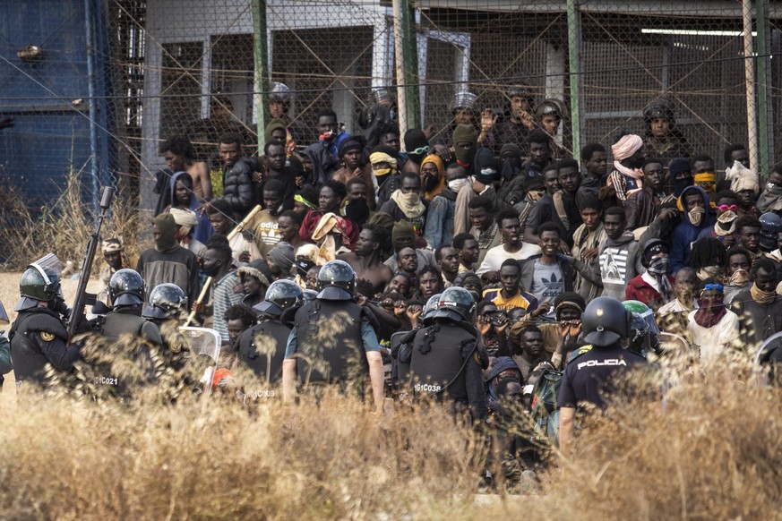 Riot police officers cordon off the area after migrants arrive on Spanish soil and crossing the fences separating the Spanish enclave of Melilla from Morocco in Melilla, Spain, Friday, June 24, 2022.  ...