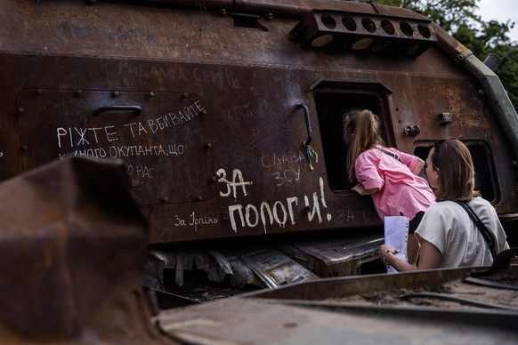 May 25, 2023, Kyiv, Ukraine: The night after Ukraine knocked out 36 drones in the sky in a Russian attack on the city a woman shows her daughter the inside of a destroyed Russian armored vehicle at Sa ...