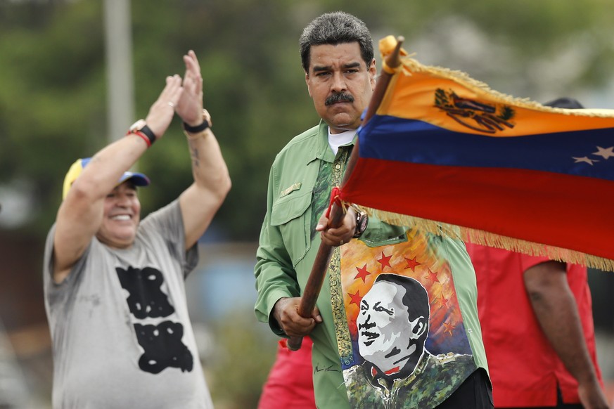 Präsident Nicolas Maduro schwingt im Chávez-Hemd die Fahne des Landes. Argentiniens Ex-Fußball-Star Diego Maradona jubelt ihm zu.