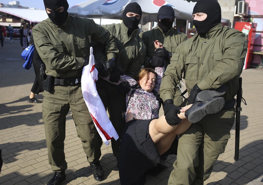 Police officer detain a woman with an old Belarusian national flag during an opposition rally to protest the official presidential election results in Minsk, Belarus, Saturday, Sept. 26, 2020. Hundred ...