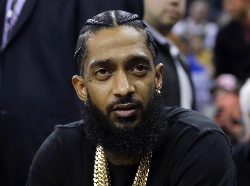 FILE - This March 29, 2018 file photo shows rapper Nipsey Hussle at an NBA basketball game between the Golden State Warriors and the Milwaukee Bucks in Oakland, Calif. Hussle was shot and killed Sunda ...