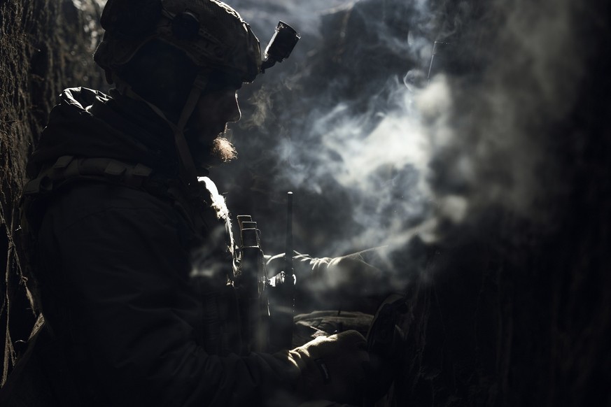 A Ukrainian soldier rests in a trench at the frontline in Donetsk region, Ukraine, Friday, Feb. 24, 2023. (AP Photo/Libkos)