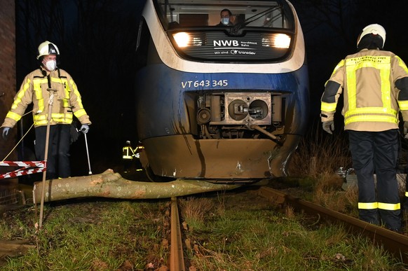 17.02.2022, Nordrhein-Westfalen, Dorsten: Feuerwehrleute r�umen unter dem Triebwagen der Nordwestbahn einen Baum weg. Die Deutsche Bahn hat wegen des Sturms Ylenia den Fernverkehr in mehreren Bundesl� ...