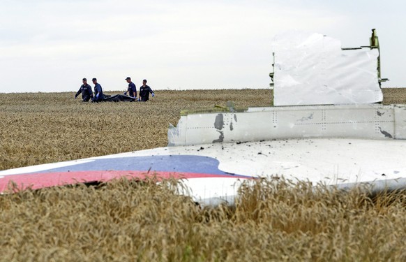 ARCHIV - 19.07.2014, Ukraine, Donezk: Einsatzkr�fte transportieren eine Trage mit einem Leichensack durch ein Getreidefeld an der Absturzstelle der Boeing 777, die als Flug MH17 der Malaysia Airlines, ...