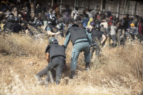 A migrant is detained by police officers on Spanish soil after crossing the fences separating the Spanish enclave of Melilla from Morocco in Melilla, Spain, Friday, June 24, 2022. Dozens of migrants s ...