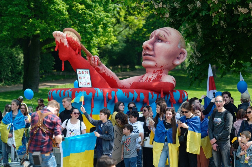 14.05.2023, Nordrhein-Westfalen, Aachen: Teilnehmer einer Demonstration gegen Proteste gegen Waffenlieferungen in die Ukraine stehen vor einer Karnevalsfigur vom russischen Präsidenten Putin in einem  ...