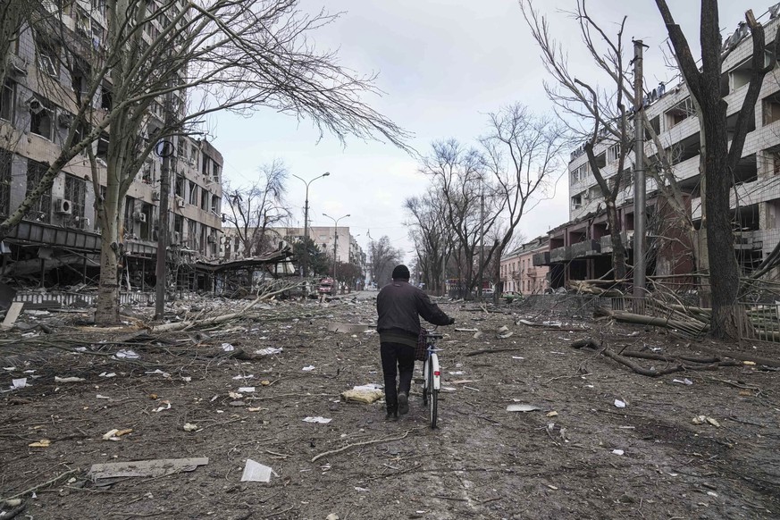 A man walks with a bicycle in a street damaged by shelling in Mariupol, Ukraine, Thursday, March 10, 2022. (AP Photo/Evgeniy Maloletka)