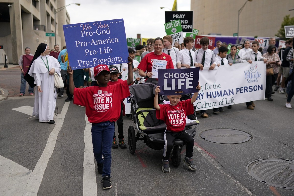 From left, Gianna Young, holding a sign that reads &quot;We Vote Pro-God Pro-America Pro-Life Pro-Freedom&quot; and her brothers Lucas and Isaac, holding a &quot;Choose Life&quot; sign, march with the ...
