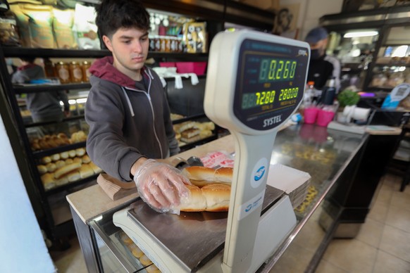 10.08.2022, Argentinien, Buenos Aires: Ein junger Verk�ufer wiegt Br�tchen in einem Laden. Die Preise kletterten im Juli gegen�ber dem Vorjahr um 71 Prozent. Die Landesw�hrung Peso wertet gegen�ber de ...